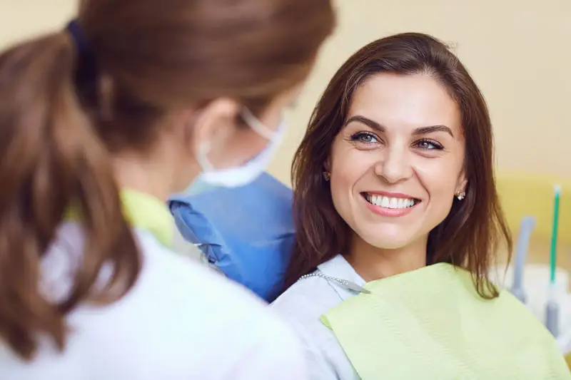 A woman sitting in a dentist chair, smiling at the dentist.