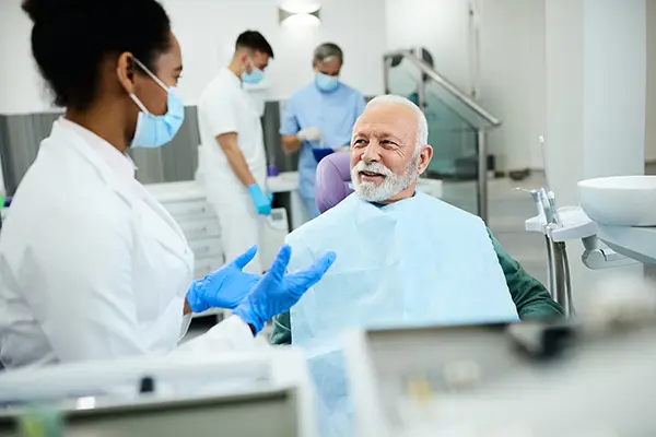 Older patient sitting in dental chair calmly discussing his oral health with his female dentist during dental implant consultation at Coulter Family Dentistry in Spokane Valley, WA Older patient sitting in dental chair calmly discussing his oral health with his female dentist during dental implant consultation at Coulter Family Dentistry in Spokane Valley, WA