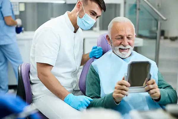 Happy, senior patient looking at his restored smile in a mirror at Coulter Family Dentistry in Spokane Valley, WA Happy, senior patient looking at his restored smile in a mirror at Coulter Family Dentistry in Spokane Valley, WA